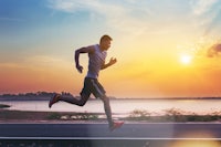 a man is running on a road at sunset
