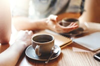 two people sitting at a table with a cup of coffee