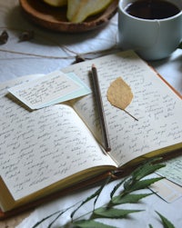 an open notebook with a pen and a cup of coffee