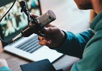 a man with a microphone in front of a laptop