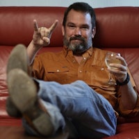 a man sitting on a red couch with a glass of wine